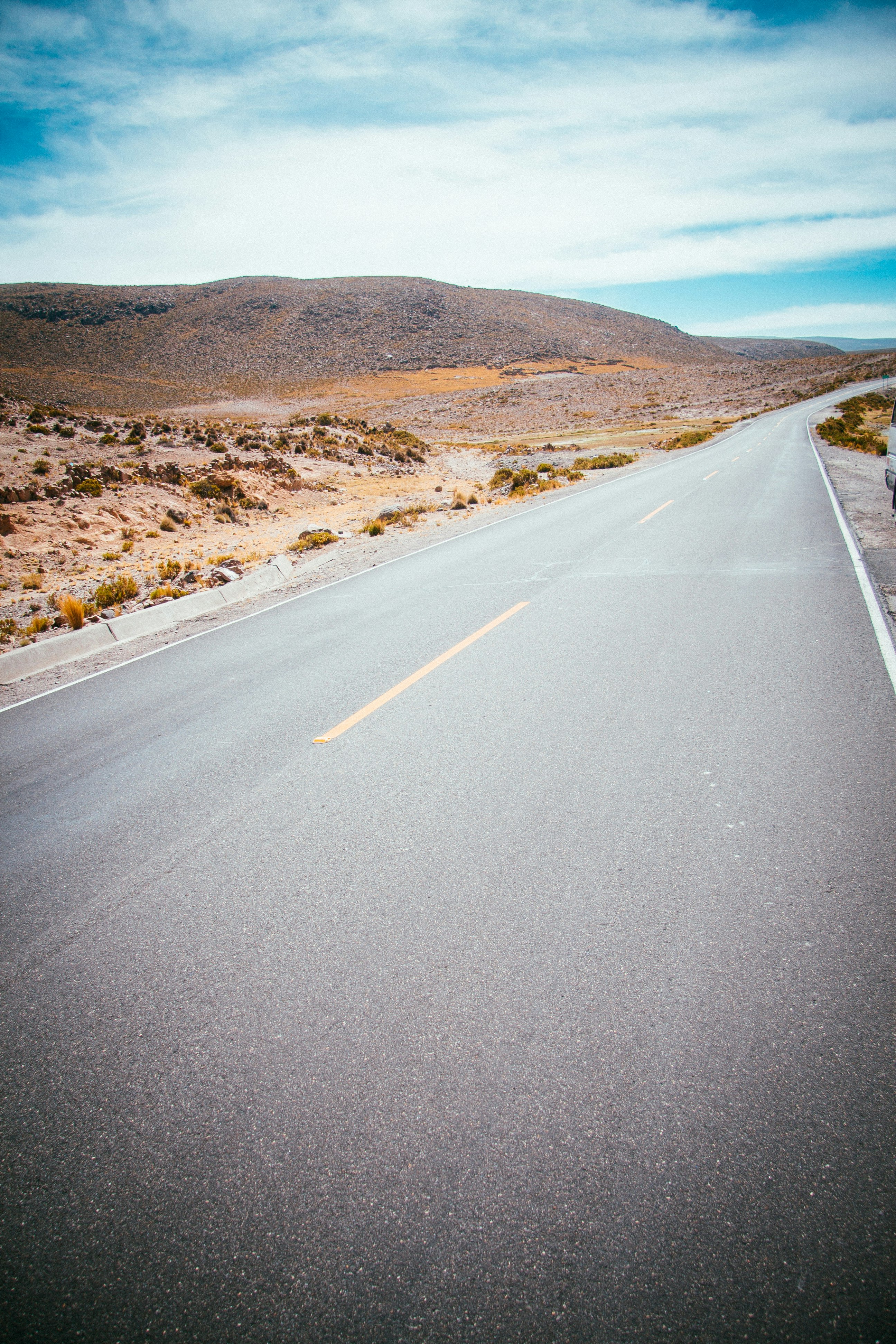 gray concrete road between mountain at daytime